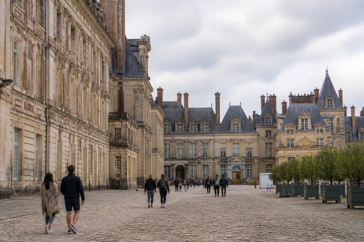 Cour du château de Fontainebleau et visiteurs devant les façades historiques